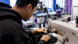 Hands sewing woven neck label onto garment collar