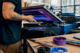 Hands applying screen print on hoodie fabric