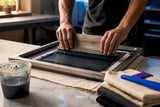 Hands applying water based ink to cotton fabric