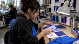 Hands comparing embroidered thread color samples